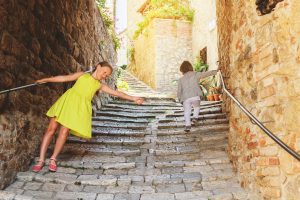 Adorable kids having fun outdoors, dancing on the streets of old italian city