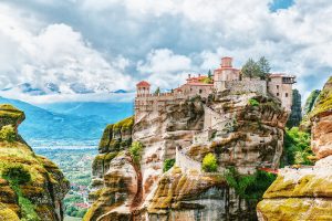 Monastery Meteora against a stunning summer view of mountains and green forest. UNESCO heritage list object.